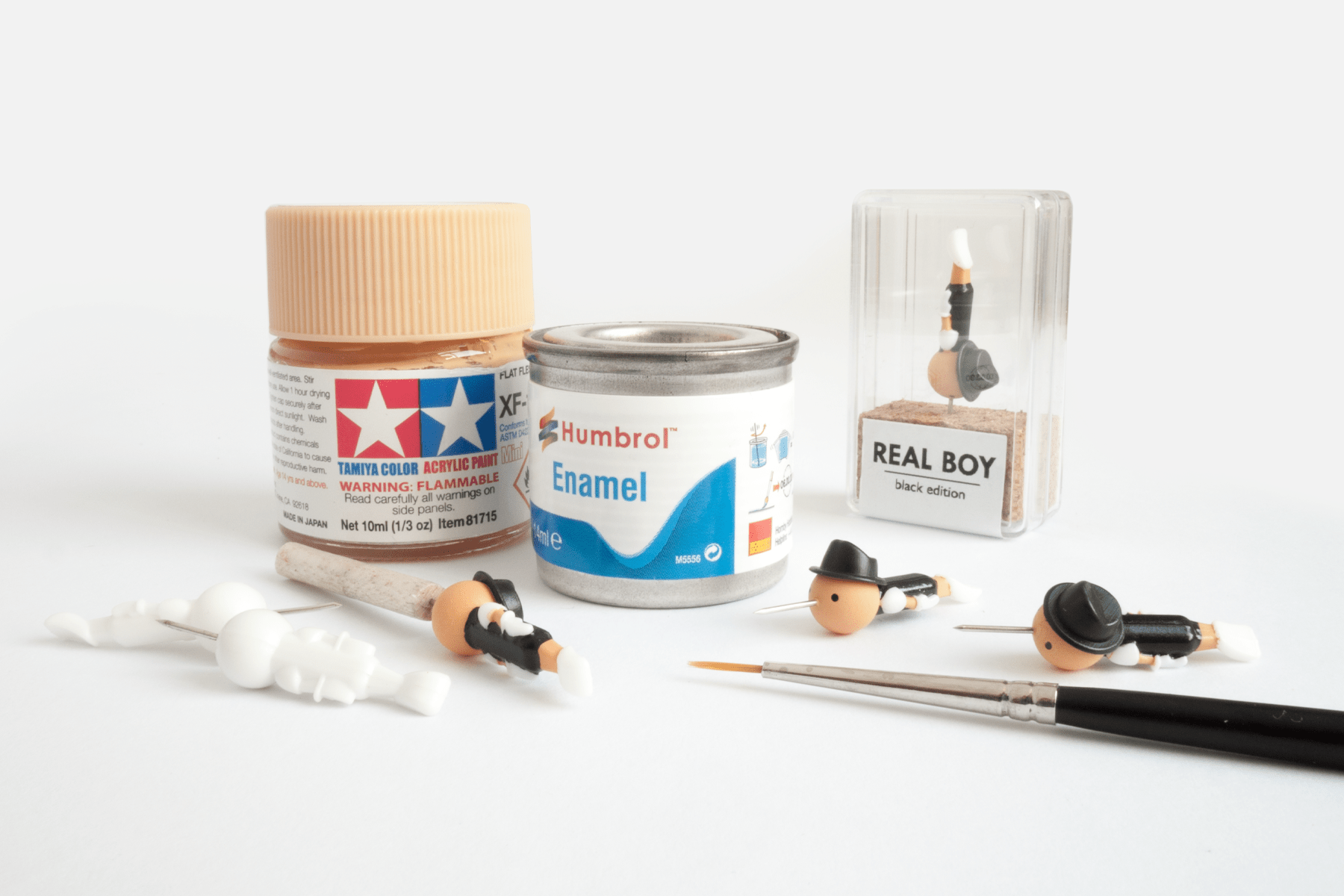 process photo of hand painted realboy pinocchio thumb tacks with paintbrushes and paints