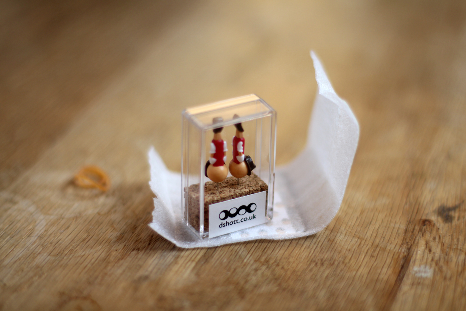 Real boy pinochio push pins in clear presentation box sat on a wooden tabletop