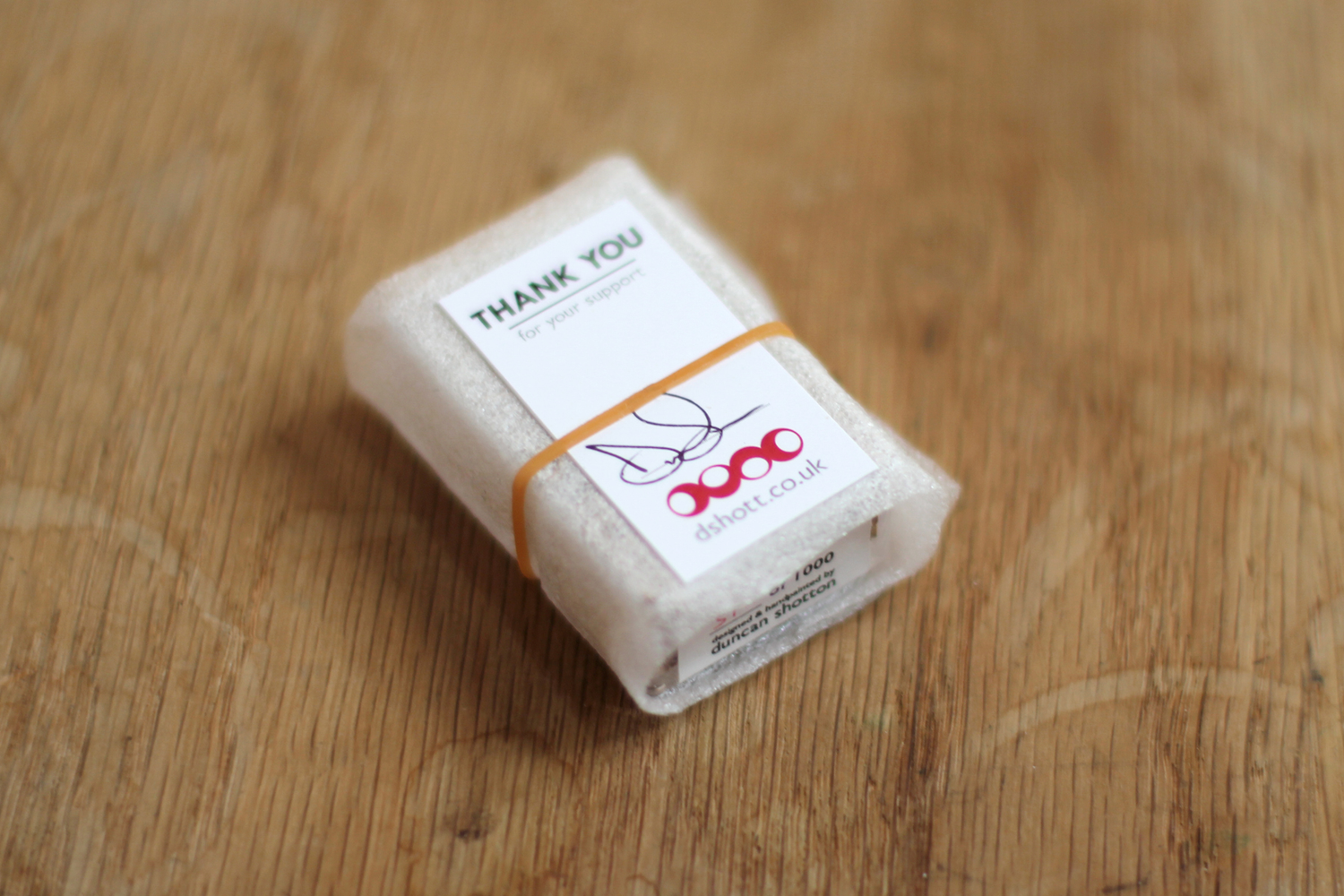 Signed thank you card held onto foam-wrapped art stationery with a rubber band