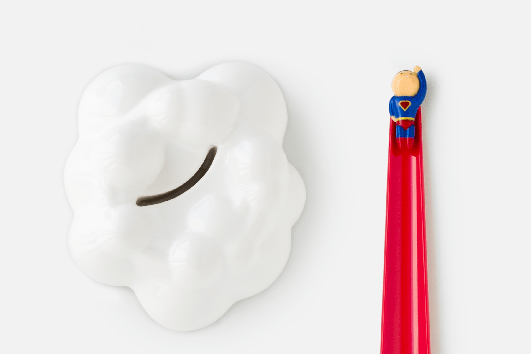 Shoeperhero (Red) laid flat next to the ceramic cloud stand that keeps it upright when not in use