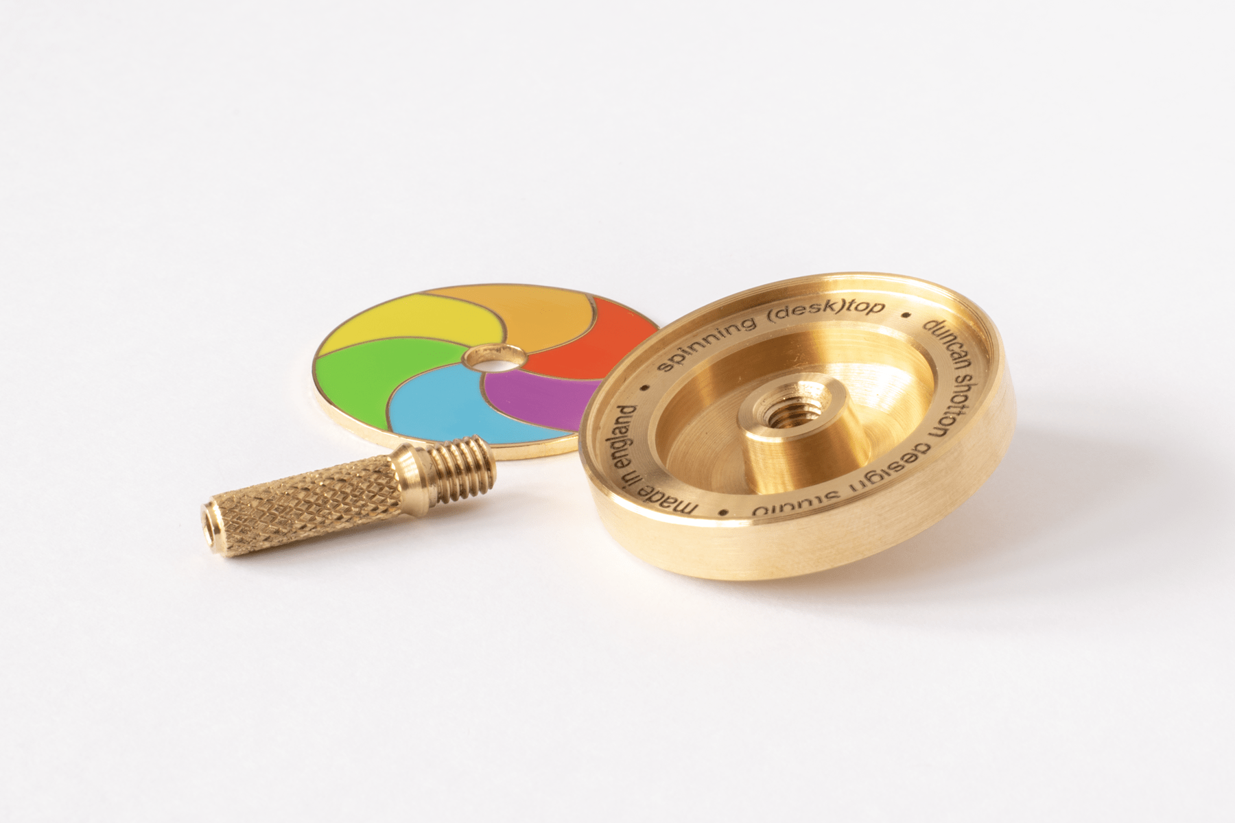 Turned brass components of an art spinning top and polished enamel spinner piece