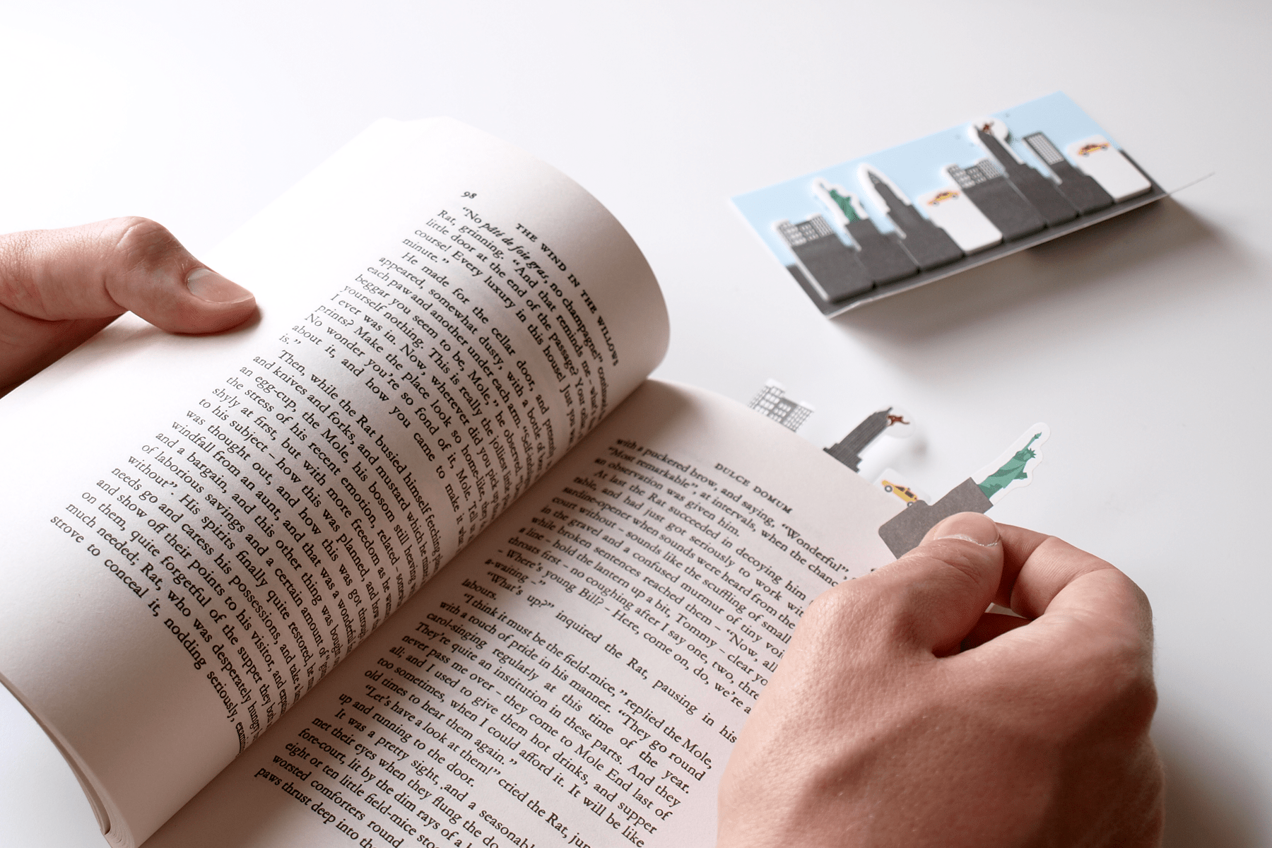 Statue of liberty paper Sticky Page Marker being placed in the page of a book to note the page