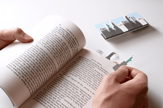 Statue of liberty paper Sticky Page Marker being placed in the page of a book to note the page