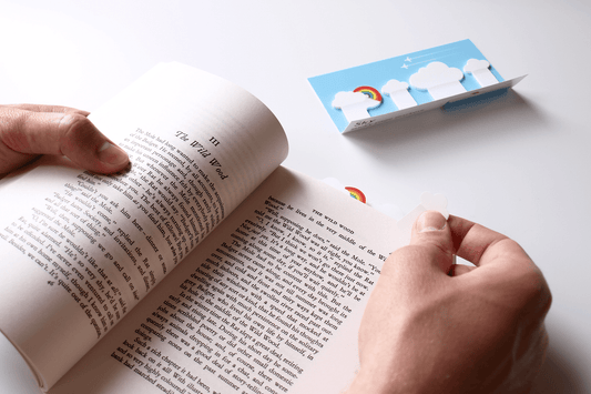 Sky (Cloud and Rainbow) Sticky Page Markers being used by a reader to mark a page of their book