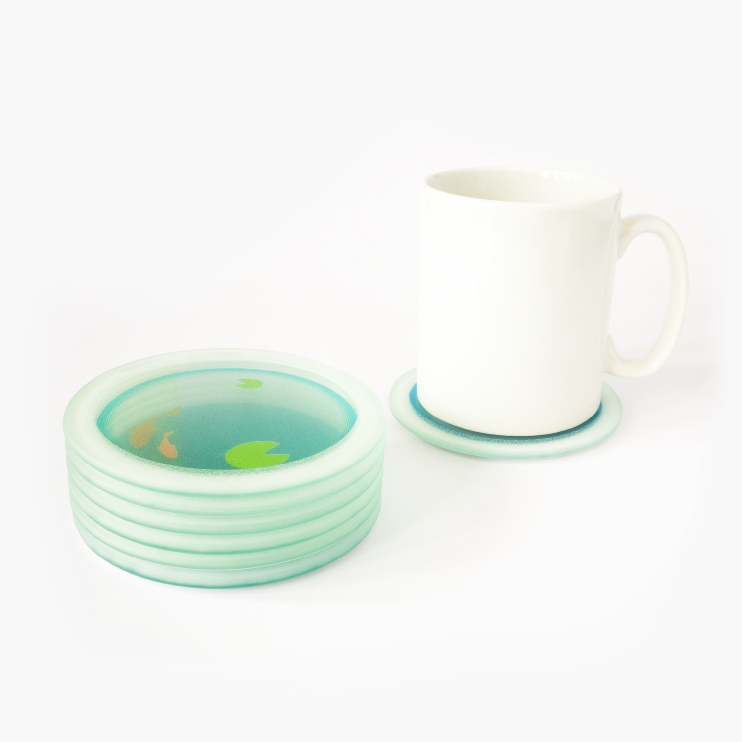 Glass coasters printed with sections of a goldfish bowl at different depths to depict a fishbowl when stacked - one from the stack shown in use under a white coffee cup