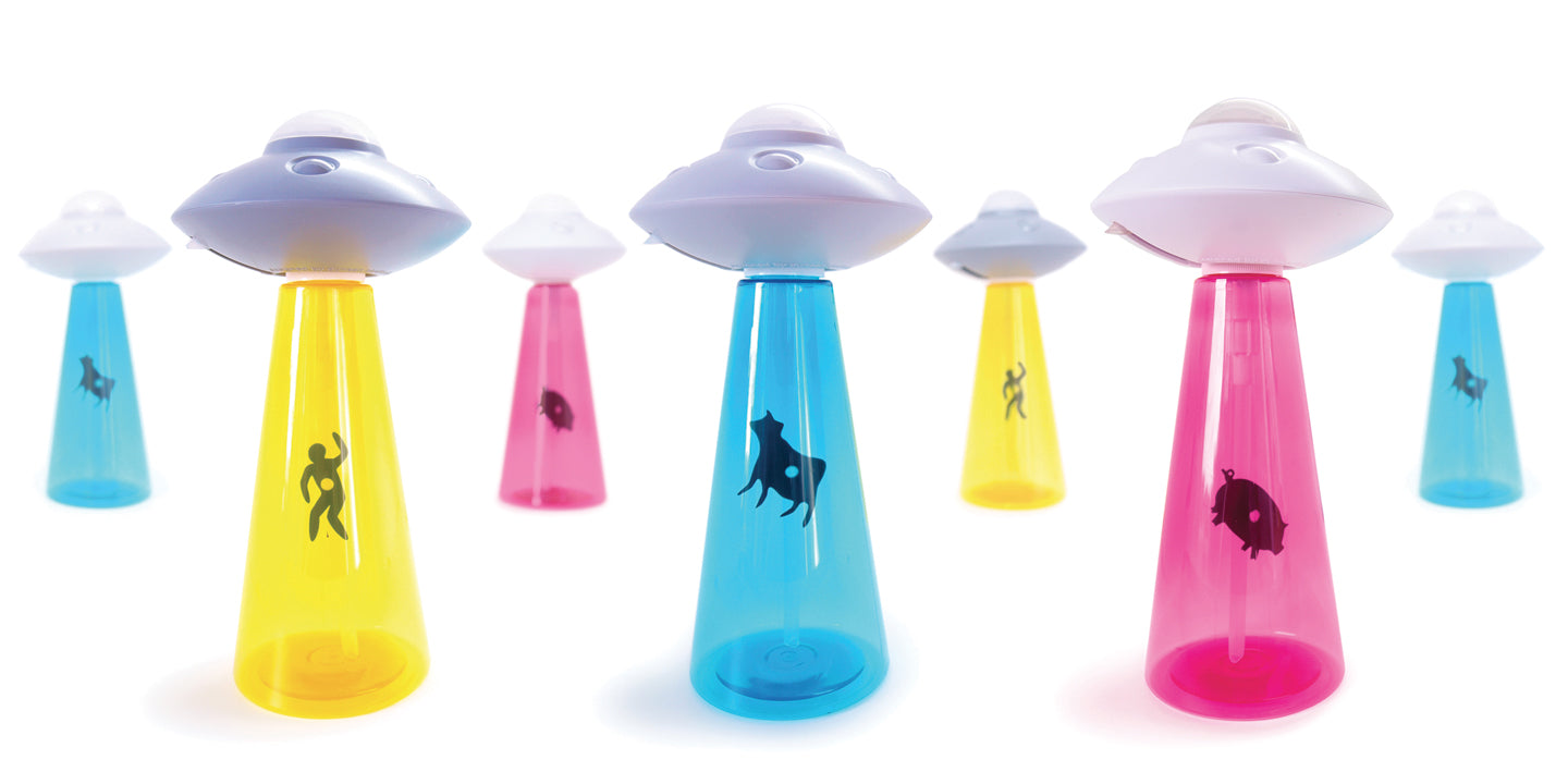 set of plastic soap dispenser bottles in the hape of UFOs with tractor beams. Each has a grey alien spaceship on top, and there are three different colour bottle bases in the shape of the tractor beam; Pink, with a black pig suspendeded in the ray, blue with a black cow suspended in the beam and yellow with the siloette of a human in black being beamed up by the spacecraft.