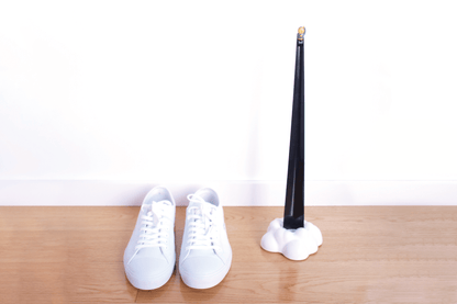 Black Shoeperhero shoehorn in it's cloud base, next to a pair of white shoes in a japanese interior